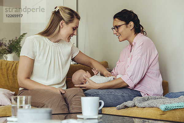 Hebamme und Mutter geben dem Neugeborenen eine Bauchmassage zur Unterstützung der Verdauung.