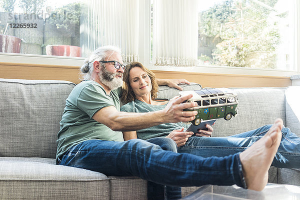 Erwachsenes Paar auf der Couch zu Hause mit Kleinbusmodell