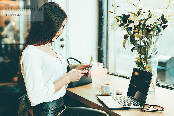 Junge Geschäftsfrau mit Smartphone im Coffee-Shop