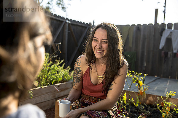Zwei glückliche junge Frauen  die im Hinterhof reden.