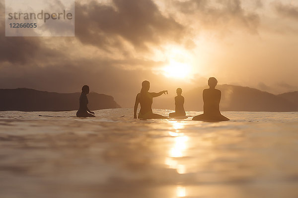 Indonesien  Lombok  Surfergruppe auf Surfbrettern bei Sonnenuntergang