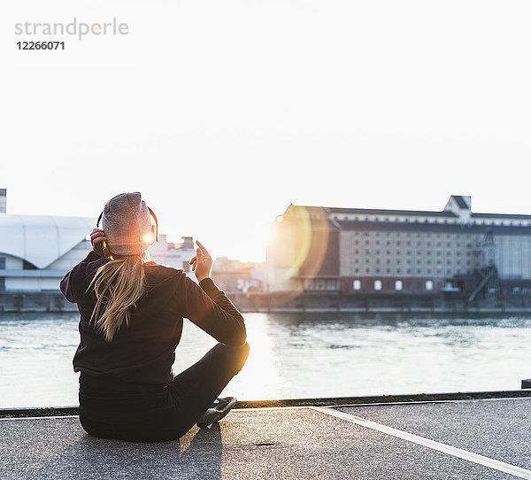 Sportliche junge Frau bei Sonnenuntergang am Flussufer in der Stadt