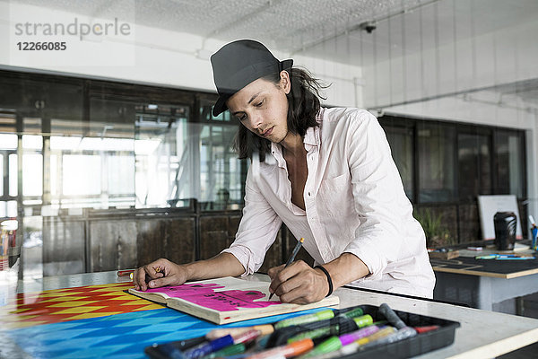 Künstler bei der Arbeit  Zeichnen in einem Notizbuch in seinem Loft-Studio