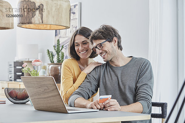 Glückliches Paar mit einer Karte mit Laptop auf dem Tisch zu Hause