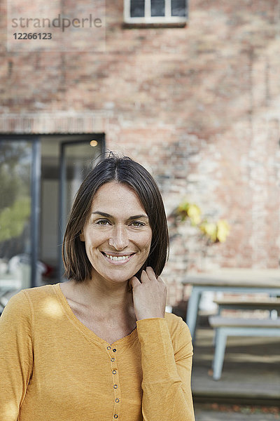Porträt einer lächelnden Frau vor ihrem Haus