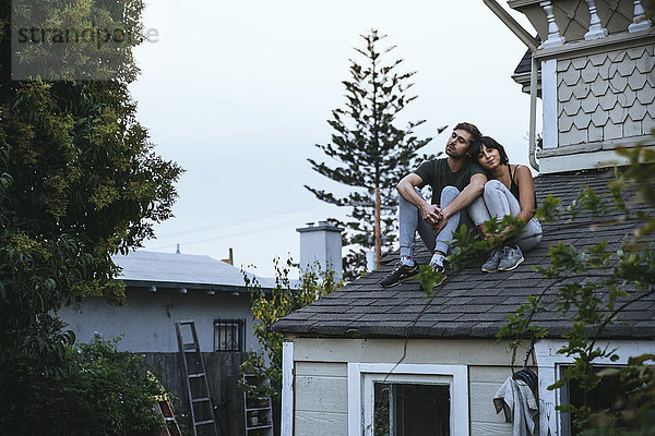 Entspanntes Paar auf dem Dach sitzend