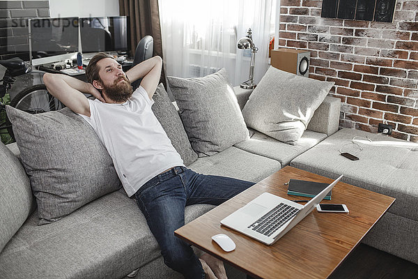 Lächelnder Mann entspannt auf der Couch zu Hause