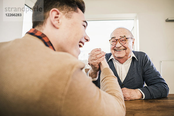 Glücklicher älterer Mann und junger Mann Armdrücken