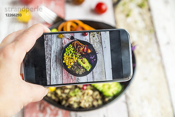 Mädchen fotografiert vegane Mittagsschale mit Handy  Nahaufnahme