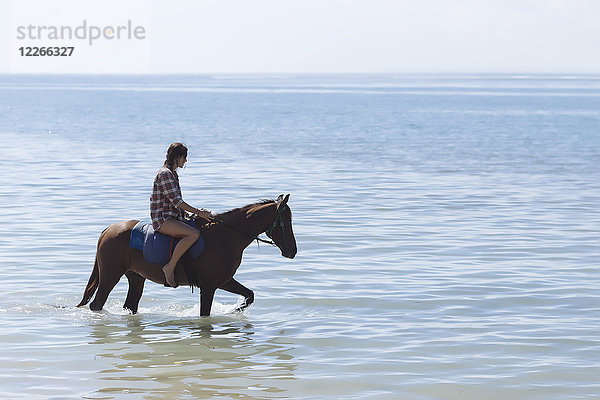 Indonesien  Bali  Frau auf einem Pferd am Strand