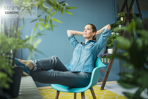 Schöne Frau in ihrem Haus sitzend  mit Pflanzen geschmückt  träumend