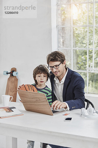 Geschäftsmann und Sohn mit Laptop am Schreibtisch