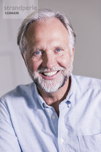 Porträt eines lachenden reifen Mannes mit blauen Augen und grauen Haaren