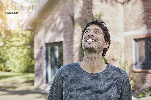 Porträt eines glücklichen Mannes vor seinem Haus