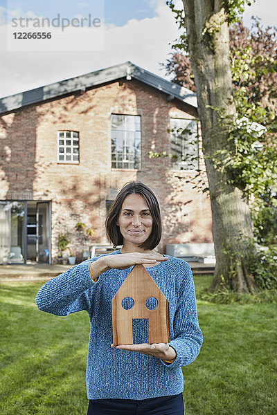 Porträt einer lächelnden Frau im Garten ihres Hausmodells