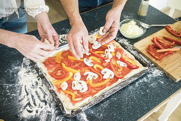Nahaufnahme eines Paares bei der Zubereitung einer Pizza in der heimischen Küche
