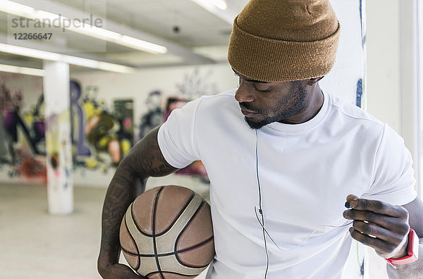 Mann mit Basketball  Wollmütze und Kopfhörer