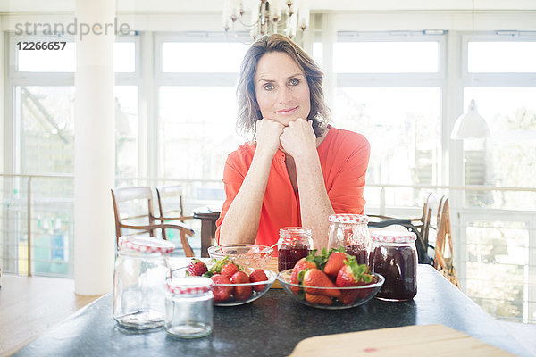 Porträt einer Frau mit hausgemachter Erdbeermarmelade zu Hause