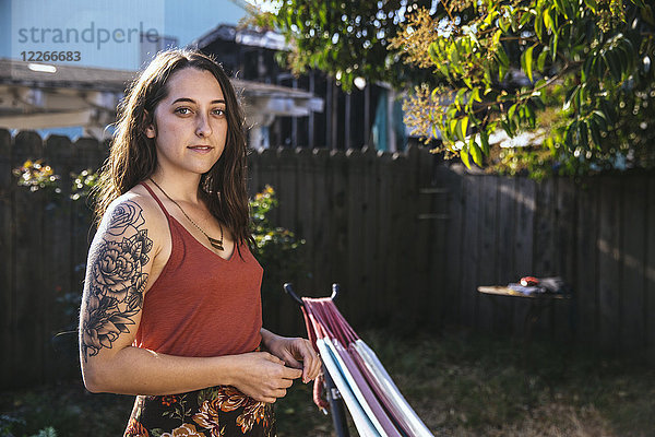 Portrait einer jungen Frau mit Tattoo im Hinterhof