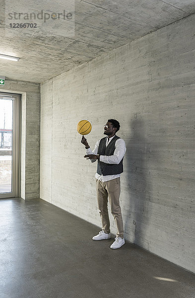Geschäftsmann beim Balancieren von Basketball im Bürogeschoss