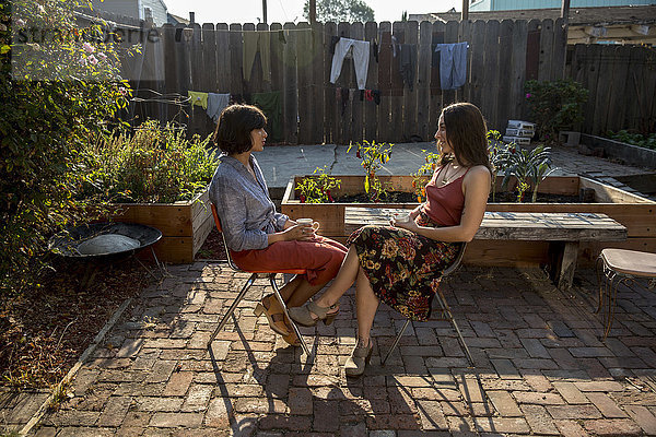 Zwei junge Frauen  die im Hinterhof sitzen und reden.