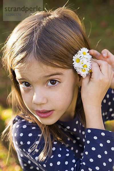 Porträt eines kleinen Mädchens mit Gänseblümchen