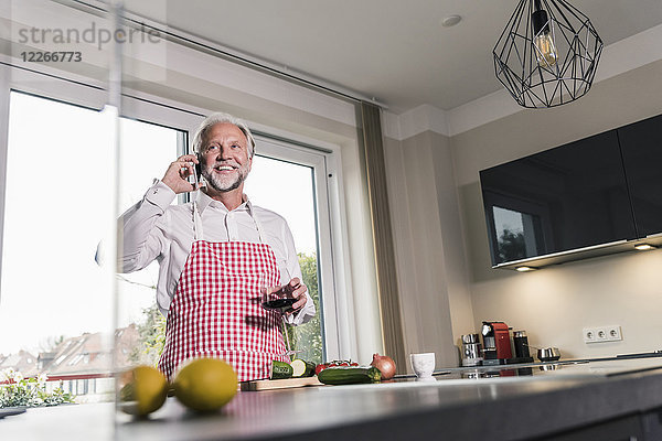 Porträt eines entspannten reifen Mannes am Telefon in der Küche