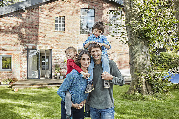 Porträt einer glücklichen Familie im Garten ihres Hauses