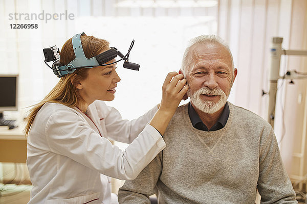 HNO-Arzt untersucht Ohr eines älteren Mannes