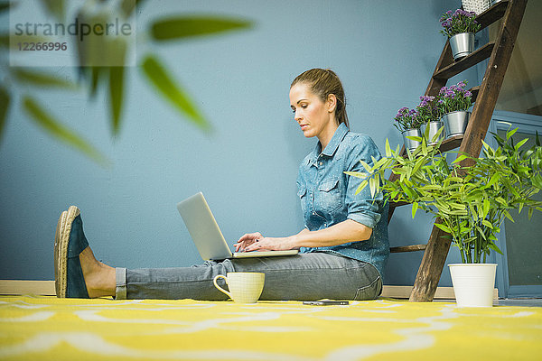 Schöne Frau in ihrem Haus  mit Pflanzen dekoriert  mit Laptop