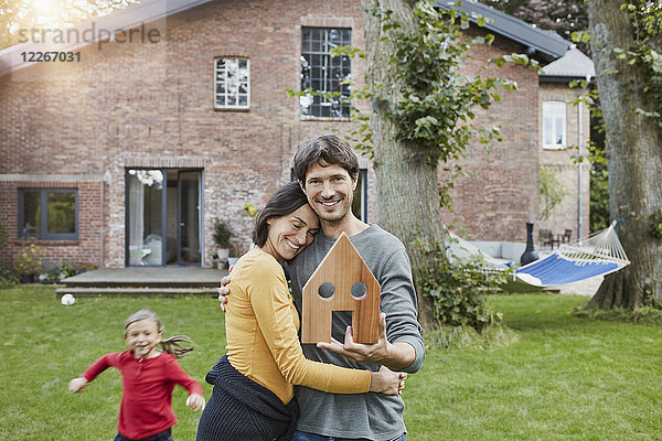 Porträt eines lächelnden Ehepaares mit Tochter im Garten ihres Hauses Modell