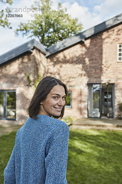 Porträt der lächelnden Frau im Garten ihres Hauses
