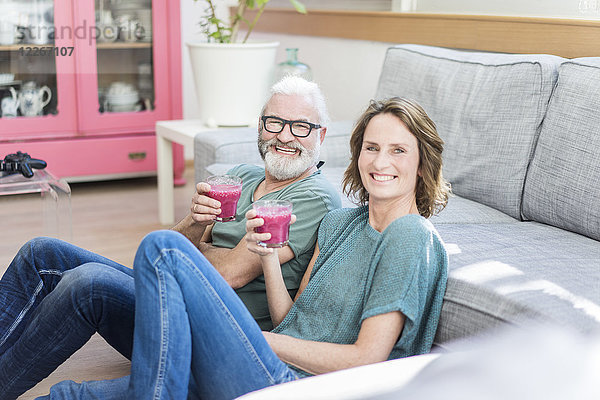 Glückliches reifes Paar mit gesunden Getränken im Wohnzimmer zu Hause