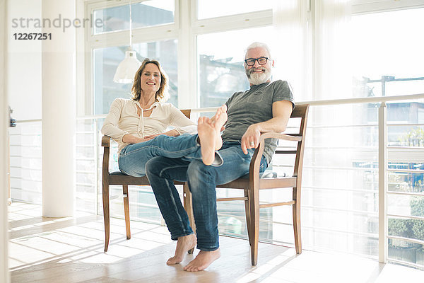 Porträt eines entspannten reifen Paares auf Stühlen zu Hause