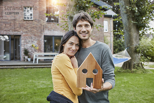 Porträt eines lächelnden Ehepaares im Garten ihres Hausmodells