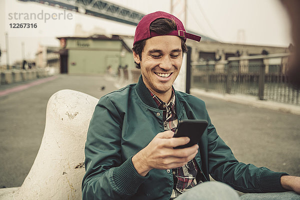 Porträt eines lächelnden jungen Mannes mit Handy
