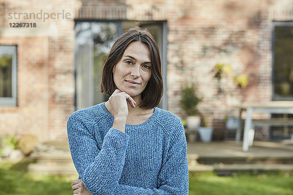 Porträt einer selbstbewussten Frau im Garten ihres Hauses