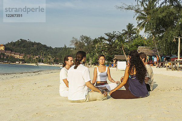 Thailand  Koh Phangan  Gruppe von Menschen  die gemeinsam an einem Strand meditieren.