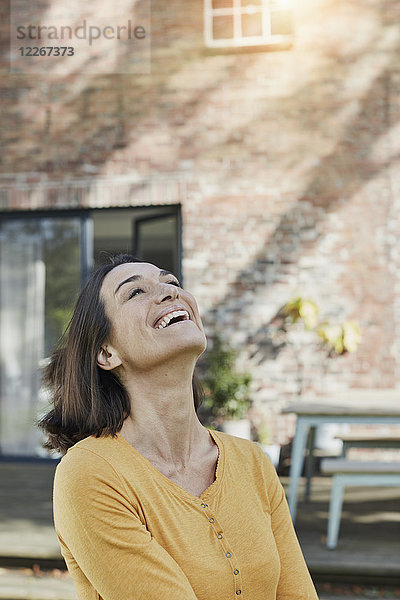 Porträt einer glücklichen Frau vor ihrem Haus