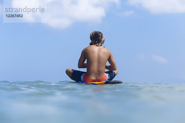 Indonesien  Bali  Surfer sitzend auf dem Surfbrett