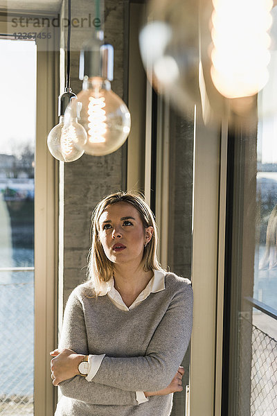 Junge Geschäftsfrau im Büro mit Blick auf Glühbirnen