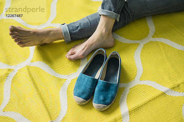 Füße und Schuhe einer Frau  entspannt auf einem gelben Teppich