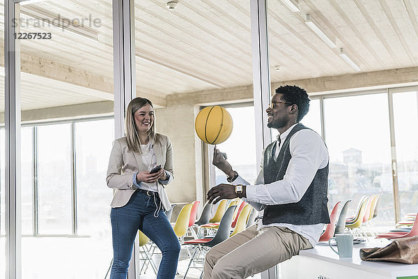 Frau betrachtet Geschäftsmann beim Basketball im Büro