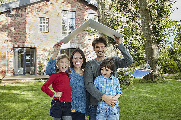 Porträt einer glücklichen Familie im Garten ihres Hausdaches