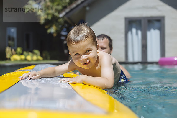 Indonesien  Bali  Vater und Junge neben dem Surfbrett im Schwimmbad