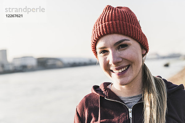 Porträt einer lächelnden  sportlichen jungen Frau am Flussufer der Stadt