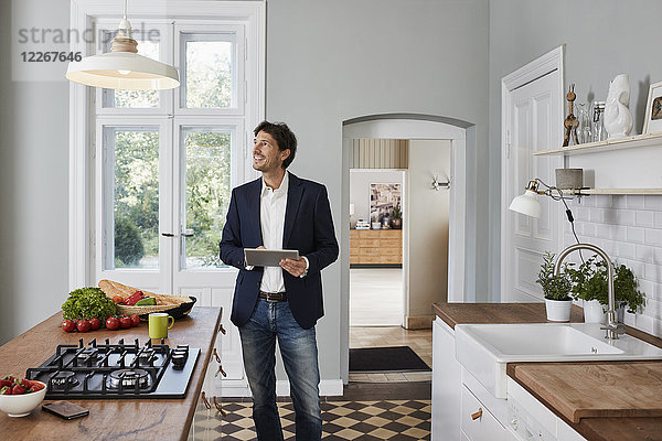 Mann mit Tablette in der Küche mit Blick auf die Deckenlampe