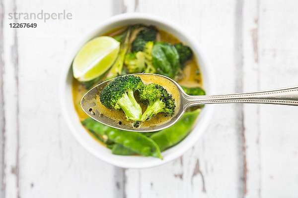 Grünes Thai-Curry mit Brokkoli  Pak Choi  Zuckerschoten  Babyspinat  Limette  Brokkoli und Sauce auf dem Löffel