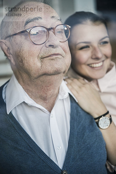 Porträt einer lächelnden jungen Frau mit einem älteren Mann am Fenster