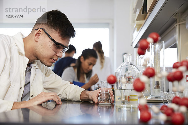 Zuversichtlicher junger  männlicher Chemiestudent von Freunden im Labor der Universität